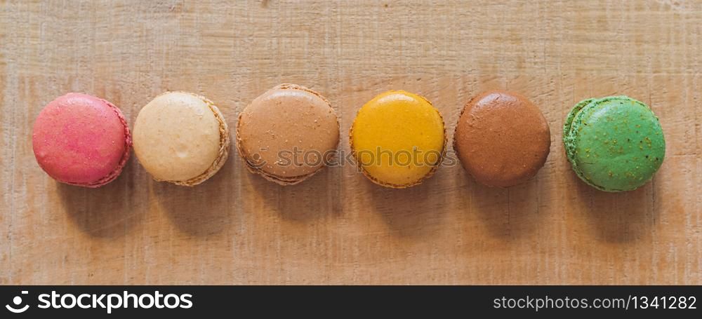 Traditional french colorful macarons in a row on table. Colorful cookies.. Traditional french colorful macarons in a row on table
