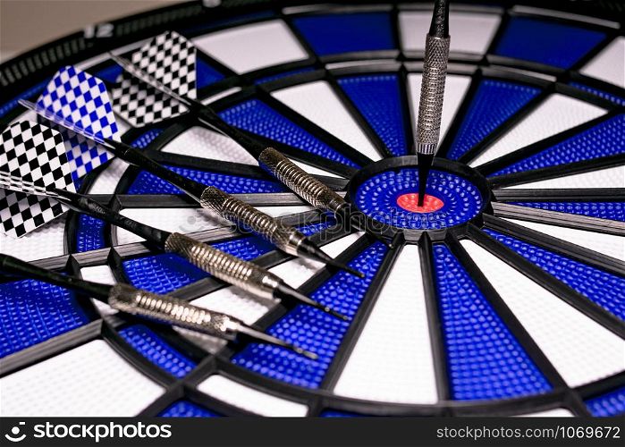 Traditional game of darts composed of target and darts in white and blue colors, with central point in red, and plastic material to avoid dangers and injuries in children