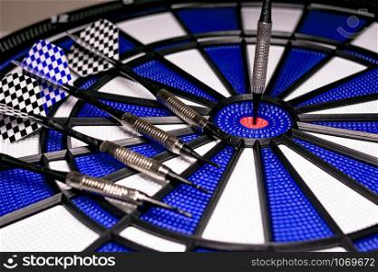 Traditional game of darts composed of target and darts in white and blue colors, with central point in red, and plastic material to avoid dangers and injuries in children
