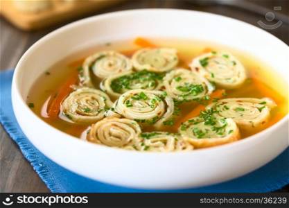 Traditional German Flaedlesuppe and Austrian Frittatensuppe based on consomme with rolls or stripes of pancake or crepe garnished with chives, photographed with natural light (Selective Focus, Focus in the middle of the soup)