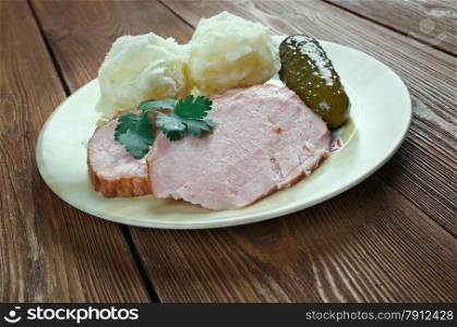 Traditional German Senfbraten with potatoes and pickles.