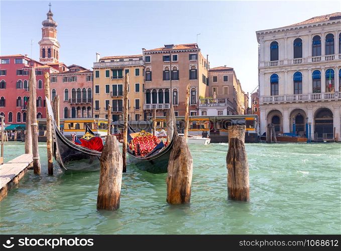 Traditional gondola boats on the grand canal on a sunny morning. Venice. Italy.. Black gondolas at the pier on the Grand Canal.
