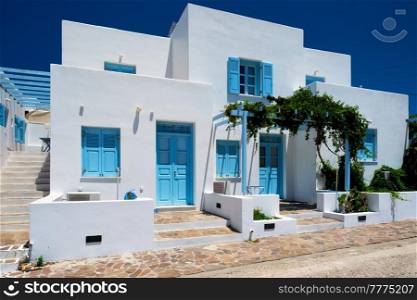 Traditional greek architecture - houses painted white with blue doors and window shutters. Pachena village, Milos island, Greece. Traditional greek architecture houses painted white with blue doors and window shutters