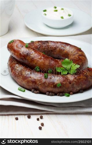 Traditional homemade coiled sausage with spices and sour cream on wooden table