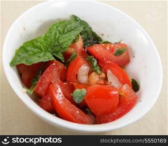 Traditional homemade Italian bruschetta, with chopped tomatoes, onion, garlic, basil leaves, oregano, olive oil, balsamic vinegar, salt and pepper in a bowl.