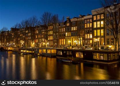 Traditional houses and houseboats in Amsterdam the Netherlands at sunset