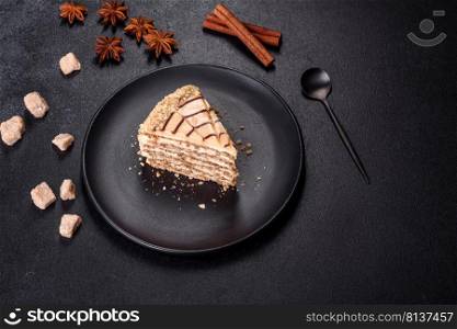 Traditional Hungarian Esterhazy cake, torte. Black background. Copy space. Esterhazy cake sliced on black plate close-up. Delicatessen sweet dessert with almond meringue dough and buttercream