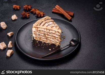 Traditional Hungarian Esterhazy cake, torte. Black background. Copy space. Esterhazy cake sliced on black plate close-up. Delicatessen sweet dessert with almond meringue dough and buttercream