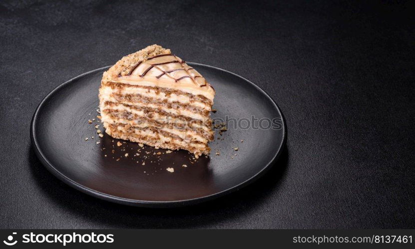 Traditional Hungarian Esterhazy cake, torte. Black background. Copy space. Esterhazy cake sliced on black plate close-up. Delicatessen sweet dessert with almond meringue dough and buttercream