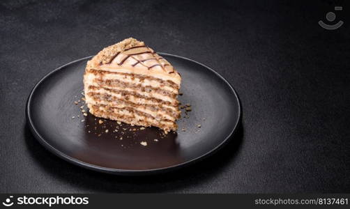 Traditional Hungarian Esterhazy cake, torte. Black background. Copy space. Esterhazy cake sliced on black plate close-up. Delicatessen sweet dessert with almond meringue dough and buttercream