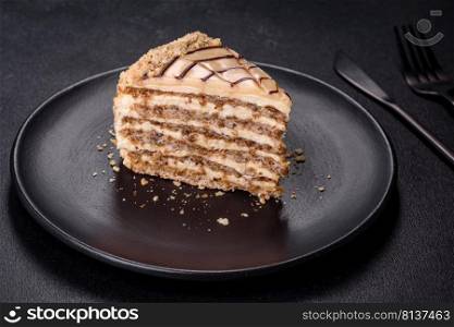 Traditional Hungarian Esterhazy cake, torte. Black background. Copy space. Esterhazy cake sliced on black plate close-up. Delicatessen sweet dessert with almond meringue dough and buttercream
