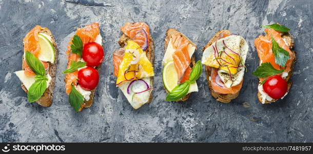 Traditional italian bruschetta.Open sandwich with salmon and vegetables. Assorted bruschetta with fish