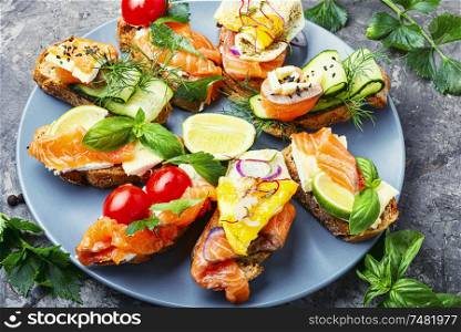 Traditional italian bruschetta.Open sandwich with salmon and vegetables. Assorted bruschetta with fish