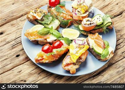 Traditional italian bruschetta.Open sandwich with salmon and vegetables. Assorted bruschetta with fish