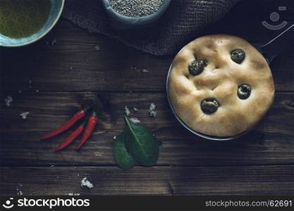 Traditional italian focaccia with green olives on wood backround.