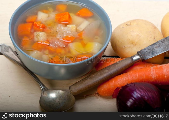 Traditional Italian minestrone soup on a rustic table with ingredients