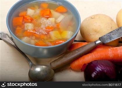 Traditional Italian minestrone soup on a rustic table with ingredients