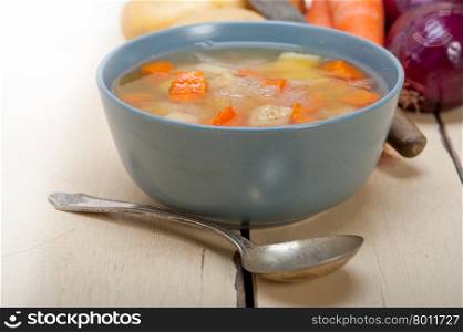Traditional Italian minestrone soup on a rustic table with ingredients