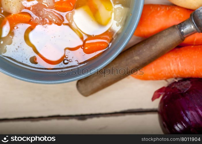 Traditional Italian minestrone soup on a rustic table with ingredients