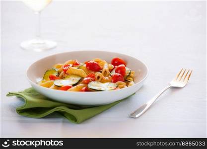 Traditional italian penne pasta with zucchini and cherry tomatoes seasoned with oil and black pepper. Italian penne pasta with zucchini and cherry tomatoes