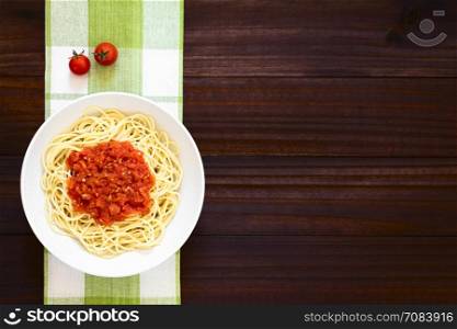 Traditional Italian Spaghetti alla Marinara (spaghetti with tomato sauce) in bowl, photographed overhead on dark wood with natural light