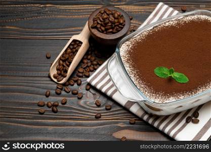 Traditional Italian Tiramisu dessert in glass baking dish and coffee beans on wooden background or table. Traditional Italian Tiramisu dessert in glass baking dish and coffee beans on wooden background