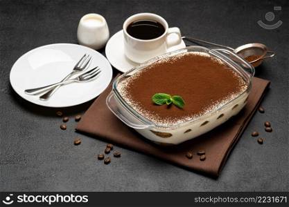 Traditional Italian Tiramisu dessert in glass baking dish and cup of fresh hot espresso coffee on concrete background or table. Traditional Italian Tiramisu dessert in glass baking dish and cup of fresh hot espresso coffee on concrete background