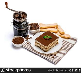 Traditional Italian Tiramisu dessert square portion on ceramic plate, coffee mill grinder and savoiardi cookies a isolated on white background with clipping path embedded. Traditional Italian Tiramisu dessert square portion on ceramic plate, coffee mill grinder and savoiardi cookies a isolated on white background with clipping path