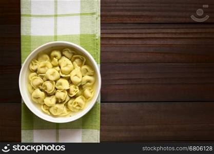 Traditional Italian Tortellini in Brodo (broth) soup, photographed overhead on dark wood with natural light