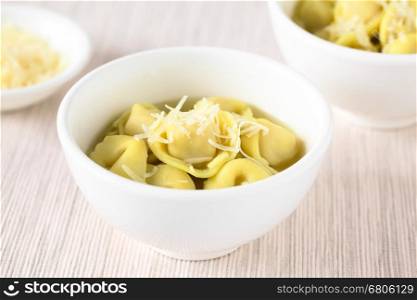 Traditional Italian Tortellini in Brodo (broth) soup with grated cheese on top, photographed with natural light (Selective Focus, Focus in the middle of the first bowl)