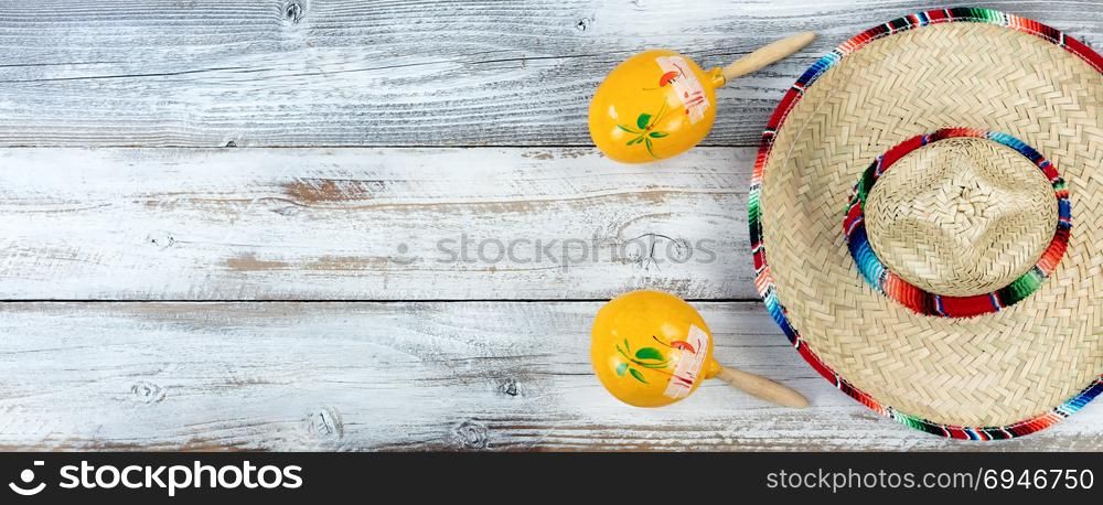Traditional large sombrero with maracas for Cinco de Mayo holiday celebration on weathered white wooden boards