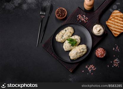 Traditional Lithuanian dish zeppelin, boiled potato dumplings stuffed with minced meat, on a black ceramic plate on a dark concrete background. Traditional Lithuanian dish zeppelin, boiled potato dumplings stuffed with minced meat