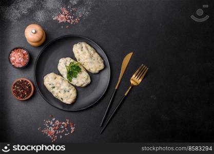 Traditional Lithuanian dish zeppelin, boiled potato dumplings stuffed with minced meat, on a black ceramic plate on a dark concrete background. Traditional Lithuanian dish zeppelin, boiled potato dumplings stuffed with minced meat