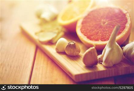 traditional medicine, cooking and ethnoscience concept - garlic, ginger, orange and grapefruit on wooden board. garlic, grapefruit, ginger, and orange on board