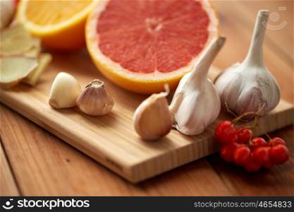 traditional medicine, cooking and ethnoscience concept - orange, grapefruit with ginger and garlic on wooden board