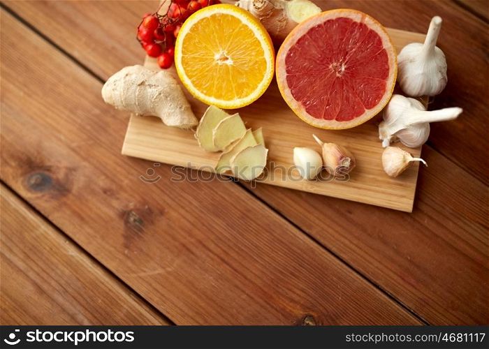 traditional medicine, cooking, food and ethnoscience concept - citrus fruits, ginger and garlic on wooden background