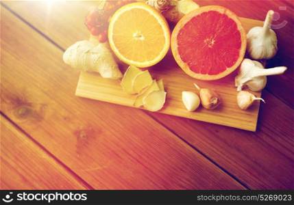 traditional medicine, cooking, food and ethnoscience concept - citrus fruits, ginger and garlic on wooden background. citrus fruits, ginger and garlic on wood