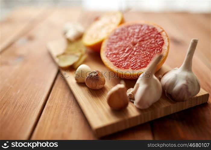 traditional medicine, cooking, food and ethnoscience concept - garlic and grapefruit on wooden board
