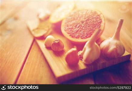 traditional medicine, cooking, food and ethnoscience concept - garlic and grapefruit on wooden board. garlic and grapefruit on wooden board