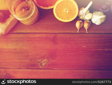 traditional medicine, cooking, food and ethnoscience concept - honey, citrus fruits with ginger and garlic on wooden background. honey, citrus fruits, ginger and garlic on wood