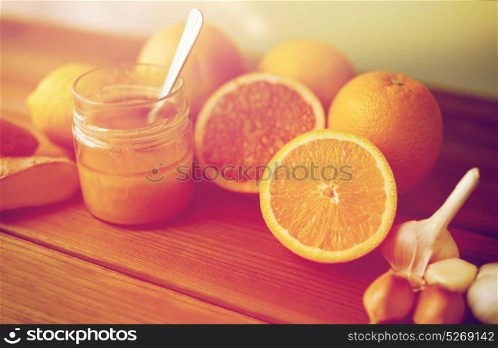 traditional medicine, cooking, food and ethnoscience concept - honey, citrus fruits with ginger and garlic on wooden table. honey, citrus fruits, ginger and garlic on wood