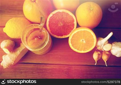 traditional medicine, cooking, food and ethnoscience concept - honey, citrus fruits with ginger and garlic on wooden background. honey, citrus fruits, ginger and garlic on wood