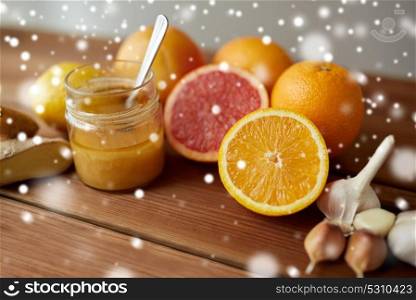 traditional medicine, cooking, food and ethnoscience concept - honey, citrus fruits with ginger and garlic on wooden table over snow. honey, citrus fruits, ginger and garlic on wood