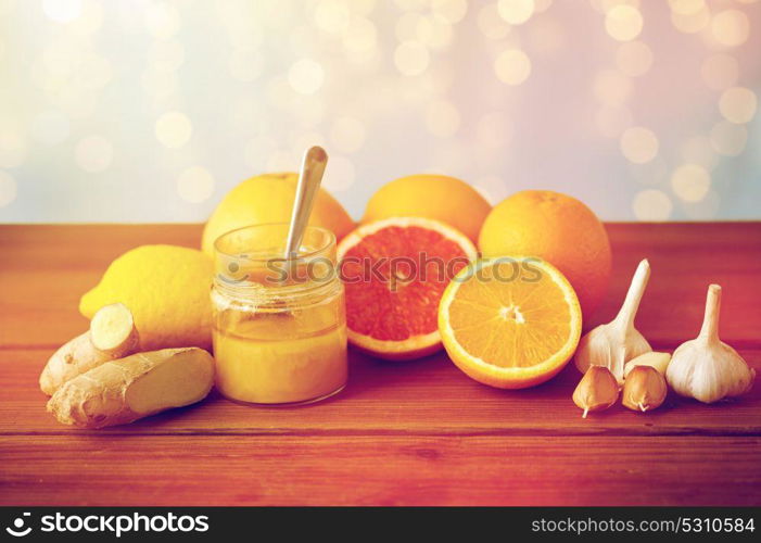 traditional medicine, cooking, food and ethnoscience concept - honey, citrus fruits with ginger and garlic on wooden table. honey, citrus fruits, ginger and garlic on wood