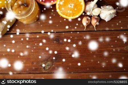 traditional medicine, cooking, food and ethnoscience concept - honey, citrus fruits with ginger and garlic on wooden background over snow. honey, citrus fruits, ginger and garlic on wood