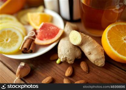 traditional medicine, healthcare and ethnoscience concept - ginger, citrus fruits, tea or honey on wooden table