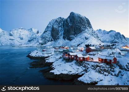 traditional norwegian red wooden house rorbu to stand on the shore of the fjord and mountains in the distance. Lofoten Islands. Norway. world travel