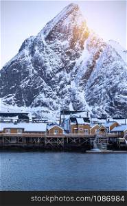 traditional norwegian wooden house rorbu to stand on the shore of the fjord and mountains in the distance. Lofoten Islands. Norway.