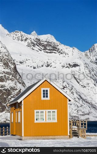 traditional norwegian wooden house rorbu to stand on the shore of the fjord and mountains in the distance. Lofoten Islands. Norway. world travel