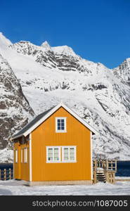 traditional norwegian wooden house rorbu to stand on the shore of the fjord and mountains in the distance. Lofoten Islands. Norway. world travel